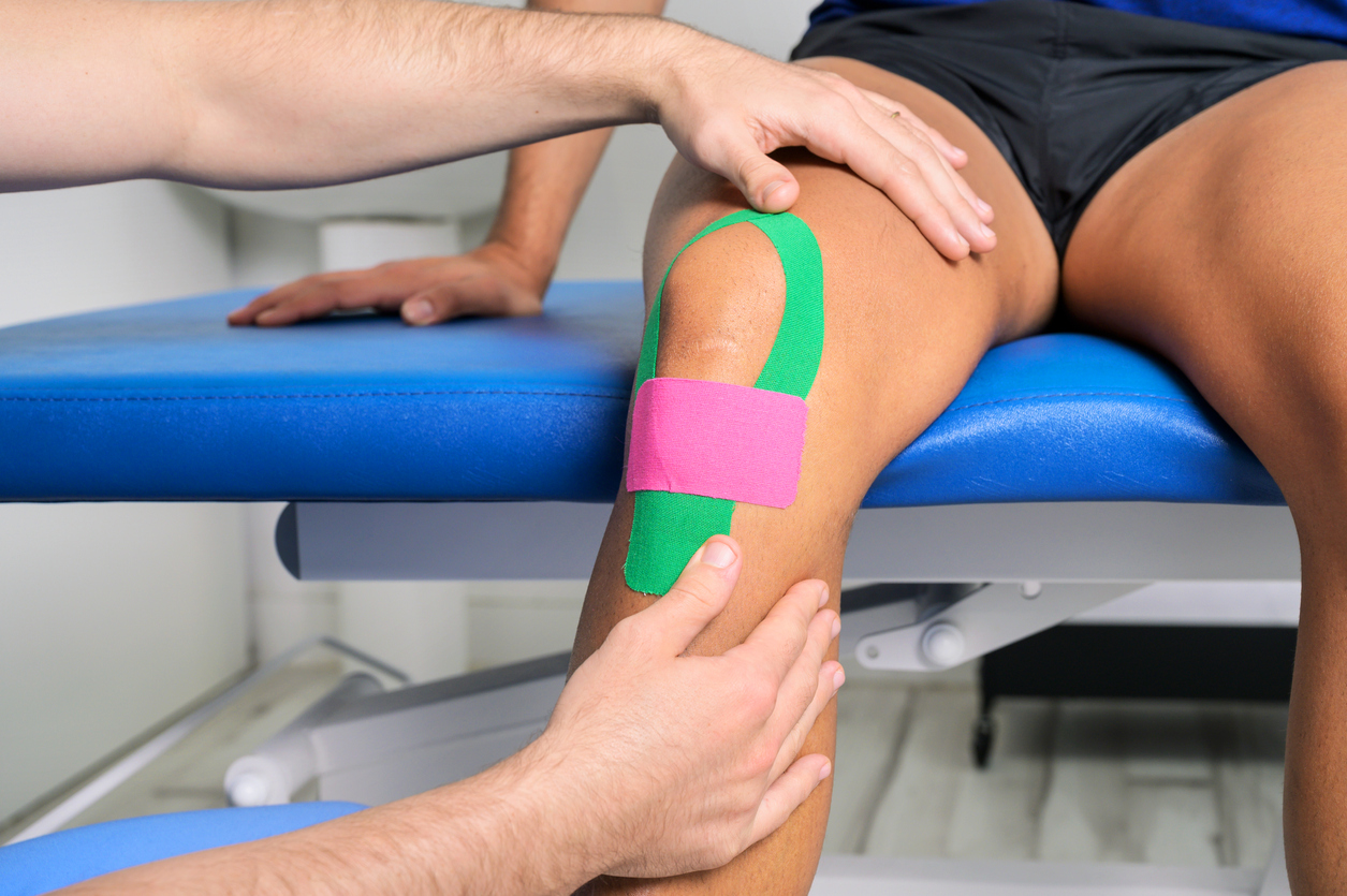 Physical therapist applying kinesio tape on male patient knee. Kinesiology, physical therapy, rehabilitation concept. close up. High quality photo